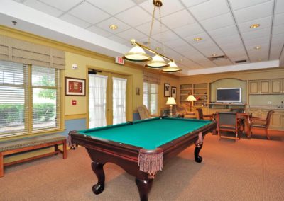 Large game room with dark wood pool table and a card table.