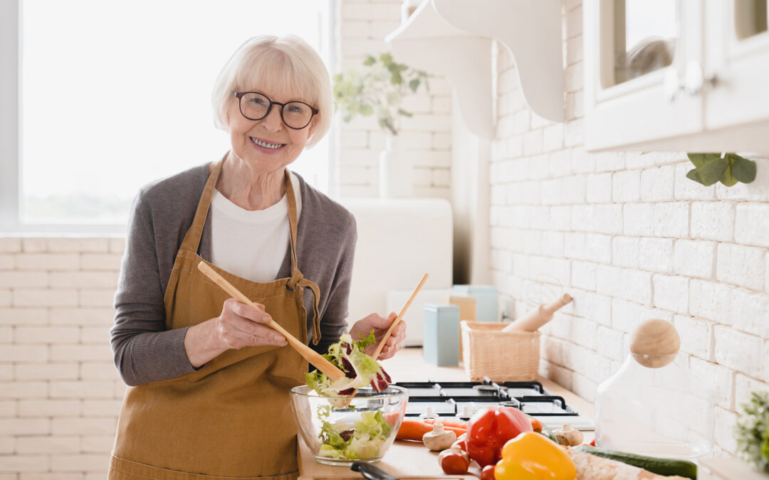 Happy smiling senior woman in apron making salad